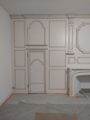 porte intérieure intégrée dans structure murale composée de panneaux moulurés et encadrement de cheminée