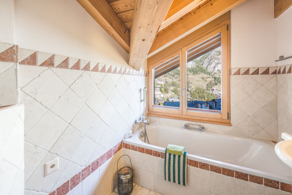 Modernes Badezimmer mit Badewanne und Bergblick in die Alpenkulisse von Zermatt.
