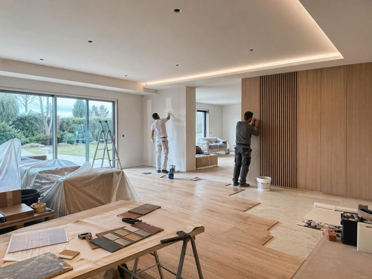 Finitions de chantier dans un salon avec pose de revêtement bois, travaux de peinture et aménagement intérieur en cours