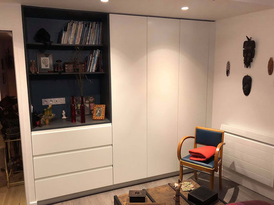 Meuble sur mesure avec placards blancs, niche bibliothèque sombre, rangements intégrés et éclairage décoratif.