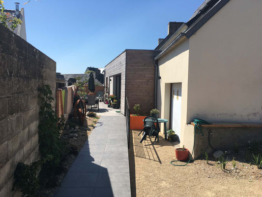 Extension de maison en ossature bois avec bardage, terrasse extérieure et cheminement accessible PMR à Plouezoc’h près de Morlaix.