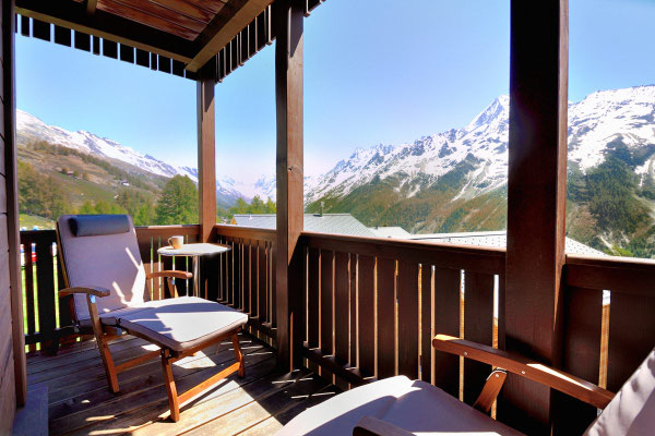 Balkon im Sommer mit Liegestuhl, dahinter Blick auf die Bergkette Richtung Lötschenlücke