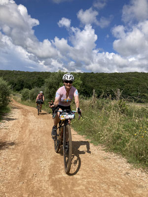 Gravelbiker auf Schotterstraße durch Hügellandschaft in Italien beim Bikepacking