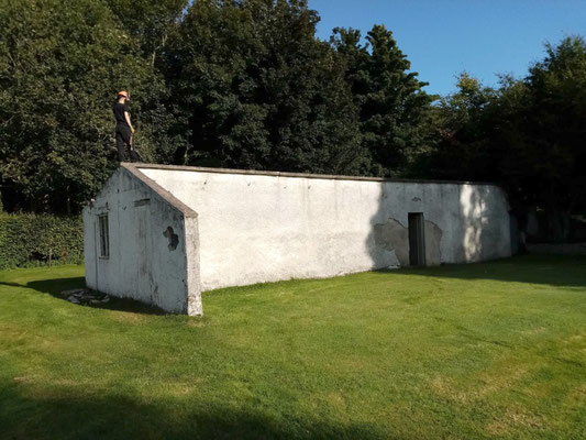 Walled outbuilding on grassy area with workman standing on top – professional landscaping and garden construction