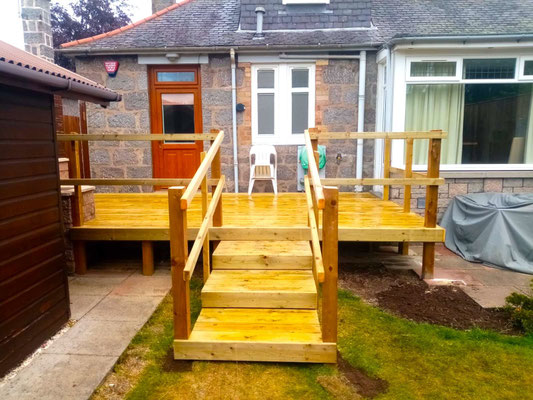 Small raised wooden deck with bannister at the back of a granite cottage in Aberdeen – bespoke garden decking installation
