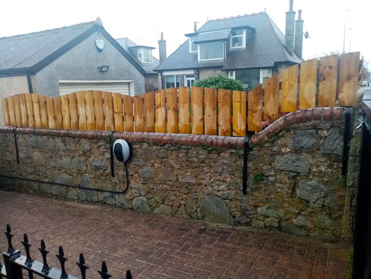 Vertical garden fence with wavy top installed on granite wall – enhanced privacy and fencing solution
