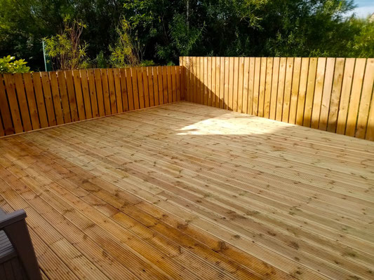Vertical board fence surrounding a newly laid garden deck – bespoke decking and fencing installation