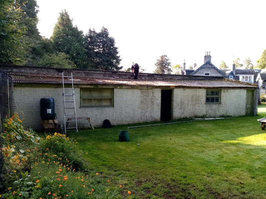 View from the opposite side of walled outbuilding on grassy area – professional garden construction and landscaping