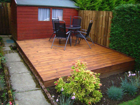 Aberdeen back garden decking beside a small shed with outdoor table and chairs.