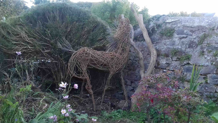 half lifesized willow horse standing in garden