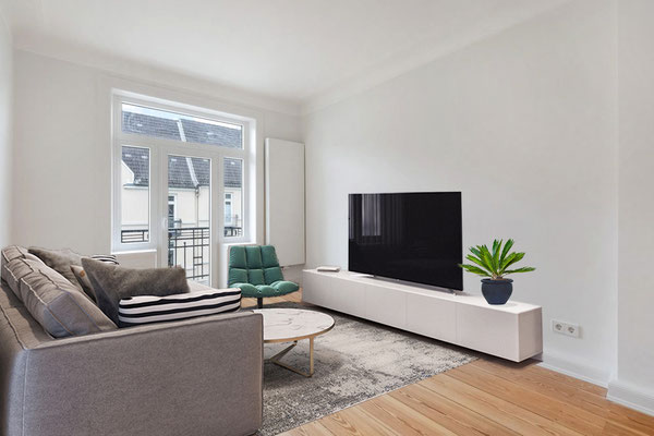 Heller Wohnraum mit sofa, sessel und tv-sideboard sowie pflanze gestagt