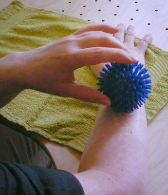Patientin trainiert Sensibilität ihres Unterarms mit einem Igelball