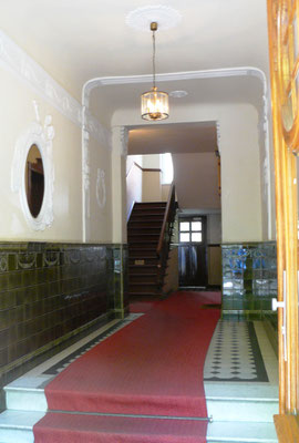 Altbau-Hausflur mit rotem Läufer, Jugendstil-Verzierungen und antiker Lampe