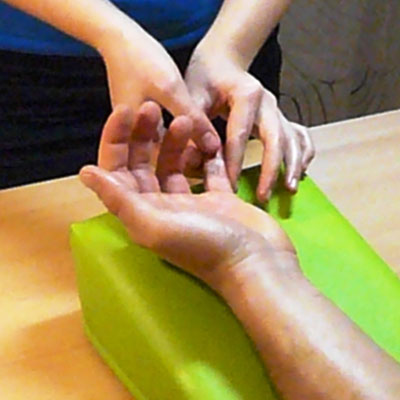 Therapeutin massiert mit ihren Händen einen vernarbten Finger