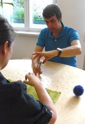 Therapeut und Patientin trainieren Feinmotorik der Hände mit Schrauben