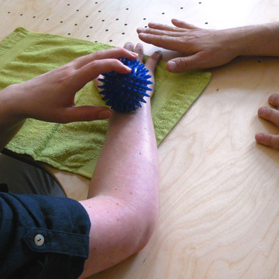 Patientin trainiert Sensibilität ihres Unterarms mit einem Igelball