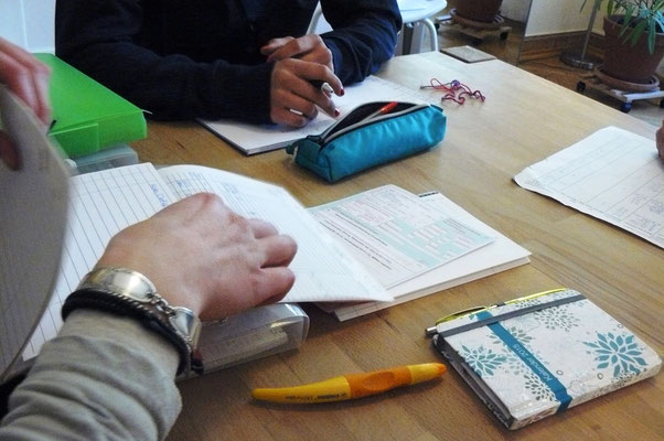 Team bespricht Patient*innen. Vor ihnen auf dem Tisch liegen Akten und Verordnungen.