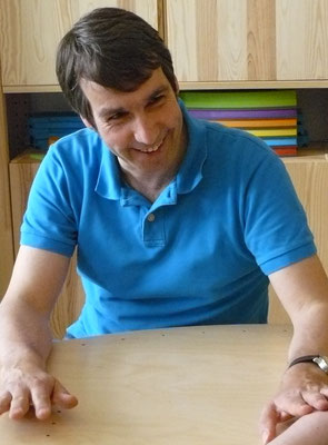 Therapeut legt freundlich lächelnd Hand auf betroffenen Unterarm der Patientin