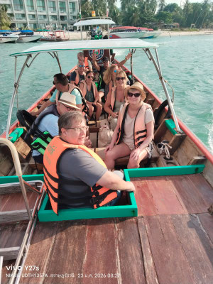 Glückliche Reisegruppe mit Schwimmwesten auf einem traditionellen thailändischen Longtailboot bei der Überfahrt.