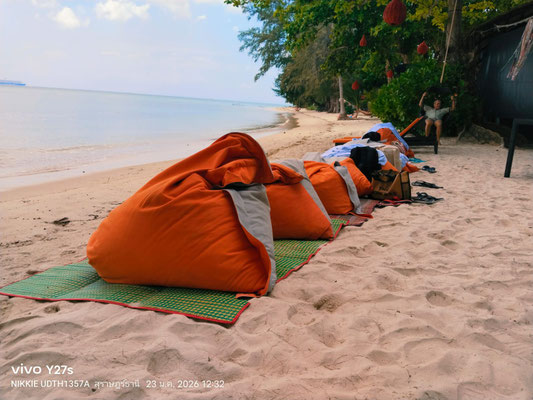 Bunte Sitzsäcke auf Matten am Sandstrand, bereit für entspannte Stunden am Meer.