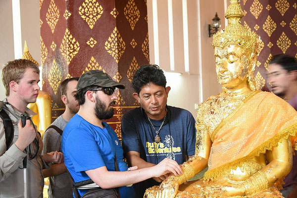 Goldplättchen auf einer Buddhastatue ertasten