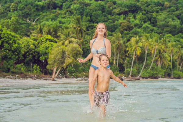 Mutter mit ihrem Sohn spielen im Wasser auf der Urlaubsinsel Koh Samui