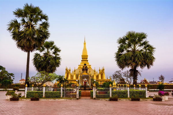 Die goldene Stupa des Pha That Luang unter blauem Himmel in Vientiane. Bildunterschrift: Das Pha That Luang ist nicht nur ein religiöses Monument, sondern das stolze Nationalsymbol von Laos.