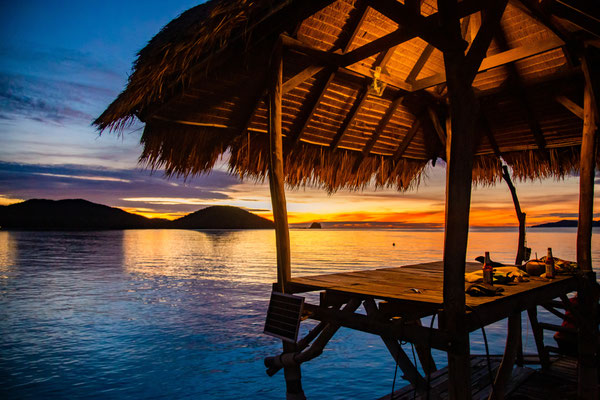  Goldener Sonnenuntergang an einem ruhigen Strand auf Koh Mak mit einer Hängematte zwischen zwei Palmen.