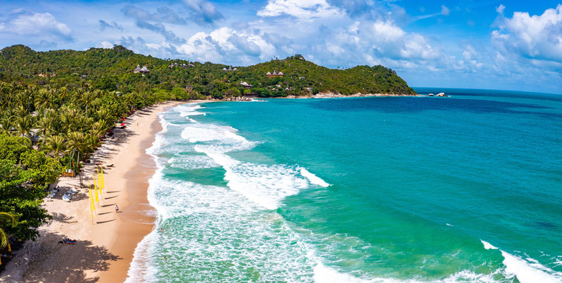 Der halbmondförmige weiße Sandstrand von Thong Nai Pan auf Koh Phangan, umgeben von dichtem tropischem Grün.