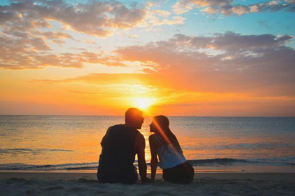 Romantischer Sonnenuntergang am Strand und einem glücklichen Urlaubspaar