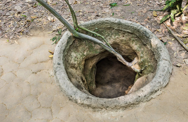 Gut getarnter runder Eingangsschacht zu den Cu Chi Tunneln im Waldboden.
