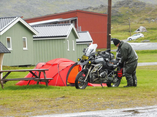  au camping, un motard monte sa tente sous la pluie. Courage !