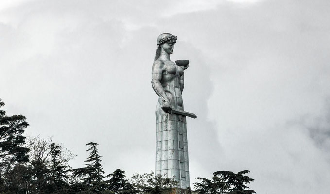Kartlis Deda, or Mother Georgia. She symbolizes the Georgian national character: in her left hand she holds a bowl of wine to greet those who come as friends, and in her right hand is a sword for those who come as enemies