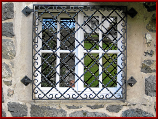 Fenstergitter als Einbruchschutz von Quadrateisen gedreht, vernietet an den Kreuzungspunkten, Enden geschmiedet