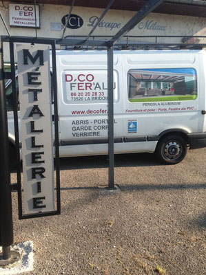 Panneau vertical en lettre métal découpée « MÉTALLERIE » devant un atelier