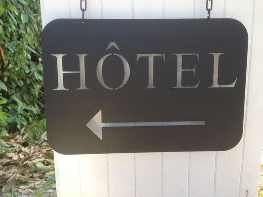Plaque signalétique en lettre métal découpée noire avec le mot « HÔTEL » en lettres capitales blanches et une flèche