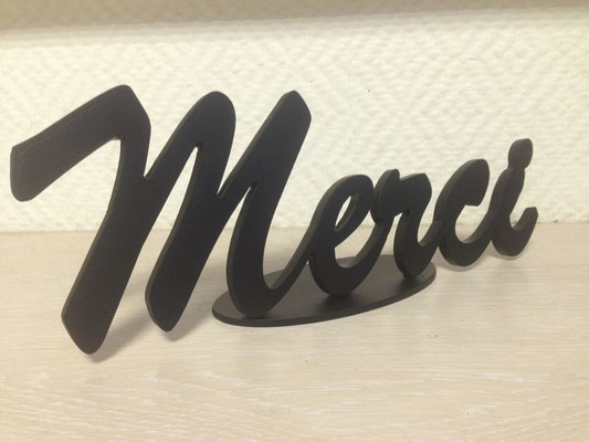 Lettre métal découpée formant le mot « Merci » en écriture manuscrite, réalisée par découpe des métaux, posée sur un fond clair.