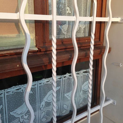 Grille métallique de protection avec barreaux verticaux idéale pour sécuriser une fenêtre.