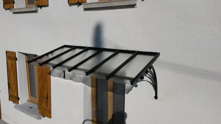 Marquise en fer forgé montée sur façade de maison, parfaite alliance entre esthétique et fonctionnalité.