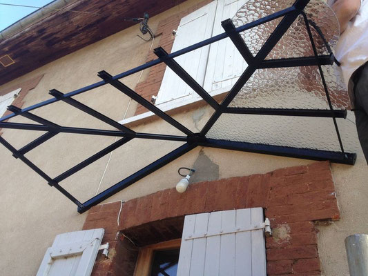 Auvent d’entrée en fer forgé avec structure travaillée et vitres transparentes