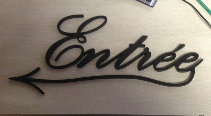 Lettre métal découpée en noir formant le mot « Entrée » en écriture cursive, réalisée par découpe des métaux