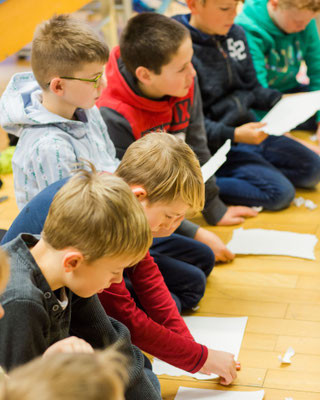 Schueler_sitzen_gemeinsam_am_Boden_und_erledigen_Aufgaben