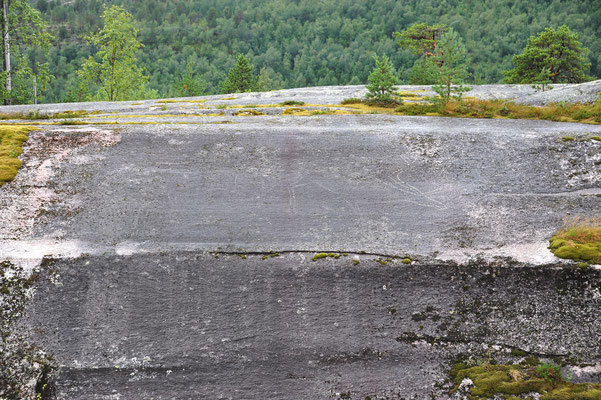 Auf der gegenüberliegenden, polierten Felswand ist eine prähistorische Felsritzung zu erkennen...