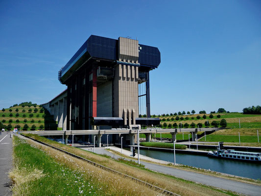 Beim Schiffshebewerk Strépy-Thieu in Belgien angekommen, kann man die Grösse des Gebäudes kaum fassen. Die Personen beim Eingang sind so klein im Vergleich, dass man sie kaum sehen kann. Lediglich der gelbe Bus links auf der Passarelle ist zu erkennen.