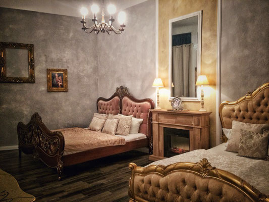 Exklusives Hotelzimmer-Design in Berlin mit strukturierter Spachteltechnik in Grau, goldenem Barock-Bett und antiken Möbeln.
