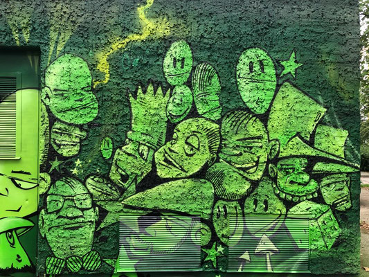Großflächiges Graffiti-Mural in Grüntönen auf einer Trafostation, das viele stilisierte Comic-Charaktere zeigt. Professionelle Fassadenkunst von Appolloart, umgesetzt deutschlandweit.