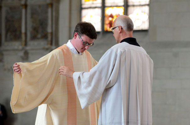 Der Dechant der St. Antoniusgemeinde, Pfarrer Norbert Mertens, kleidet den Diakon in sein neues Gewand.