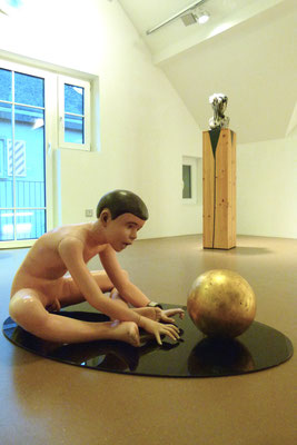"Der Traum des Künstlers", 100x60x46cm, Öl, Blattgold auf Wachs, 2000 (Sicherheitsglas), Hintergrund: "Pechmarie",h 35cm, Bitumen, Daunen auf Wachs/Terrakotta, 2009 (Holzsockel)
