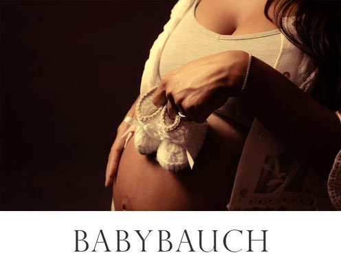 Babybauch mit kleinen Babyschuhen vor dunklem Hintergrund – Schwangerschaftsfoto im Studio in Erlangen