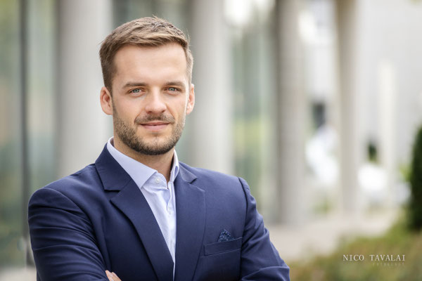 Businessfoto eines Mannes im blauen Anzug mit verschränkten Armen im Freien, moderner Look